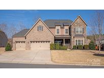 Charming two-story home features a stone and brick facade, a well-manicured lawn, and a spacious three-car garage at 865 Kathy Dianne Dr, Fort Mill, SC 29707