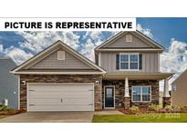 Charming two-story home featuring stone accents, a two-car garage, and a welcoming front porch. The property boasts curb appeal at 104 Woodhall Way, Troutman, NC 28166