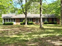 Charming single-story brick home featuring a well-manicured lawn and mature trees providing ample shade at 1330 College Ave, Shelby, NC 28152