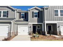 Charming two-story townhouse featuring a one-car garage, gray siding, and brick accents for added curb appeal at 1748 Braemar Village Dr, Monroe, NC 28110