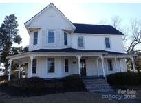 Charming two-story home featuring a welcoming wrap-around porch and mature landscaping at 201 W Rice St, Landis, NC 28088