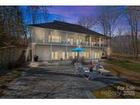 A two-story home features a stone patio with lounge chairs and a table with seating for outdoor relaxation at 213 Patternote Rd, Mooresville, NC 28117