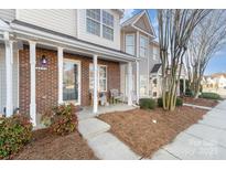 Inviting front porch of a townhome featuring brick accents and cozy seating area at 2511 Brackley Nw Pl # 1013, Concord, NC 28027
