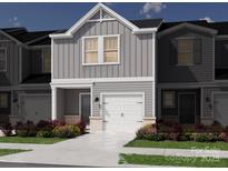 New construction townhome featuring light gray siding, a white garage door, and colorful landscaping at 5009 Kellaher Pl, Charlotte, NC 28216