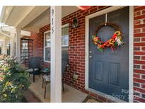 Inviting front entrance with brick facade, decorative wreath, and covered porch with seating at 915 Tj Dr, Monroe, NC 28112