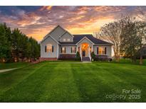 Stunning two-story home featuring lush green lawn and charming curb appeal at sunset at 12860 Westmoreland Farm Rd, Davidson, NC 28036