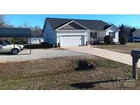 Charming single-story home featuring a two-car garage and a well-maintained lawn at 207 Planters Row Rd, Iron Station, NC 28080