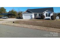 Charming single-story home with a well-maintained lawn, attached garage, and convenient carport at 207 Planters Row Rd, Iron Station, NC 28080