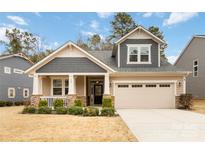Charming home boasts a two-car garage, covered front porch with stone accents, and manicured landscaping at 488 Sandbar Pt, Clover, SC 29710