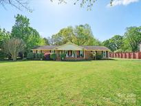 Charming one-story brick home featuring a covered front porch and a lush green lawn at 6349 Lebanon Rd, Mint Hill, NC 28227