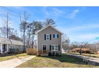 Charming two-story home featuring gray siding, black shutters, a small porch and a well-maintained lawn under a clear blue sky at 1070 Redleaf Trl, Lincolnton, NC 28092