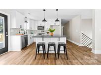 Bright kitchen features white cabinets, stylish backsplash, island with seating, and modern pendant lighting at 205 Redding Rd, Stanley, NC 28164
