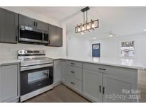 Bright kitchen features gray cabinets, stainless appliances, white counters, and new pendant lighting at 345 Grice St, Shelby, NC 28150