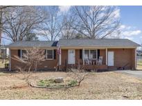 Charming brick home with a covered front porch, rocking chairs, and an American flag at 437 Valley St, Stanley, NC 28164