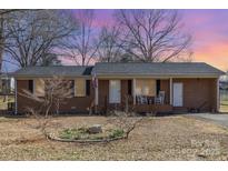 Charming brick home with a covered front porch, rocking chairs, and an American flag at 437 Valley St, Stanley, NC 28164