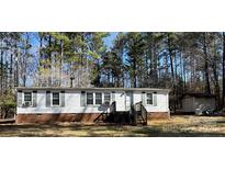 Cozy single-story home featuring white siding, dark shutters, and a brick foundation, nestled amongst a mature tree line at 4946 A Tinkers Creek Rd, Edgemoor, SC 29712