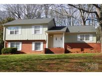 Charming two-story home with red brick base, a green lawn, and white-framed windows at 7515 Riding Trail Rd, Charlotte, NC 28212