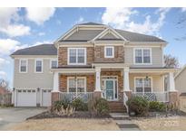Charming two-story home featuring a stone and siding exterior, a welcoming front porch, and an attached two-car garage at 12441 Morning Creek Ln, Charlotte, NC 28214