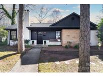 Charming single-story home with a stone facade, painted white brick, and a cozy front porch swing at 1839 Woodland Dr, Charlotte, NC 28205