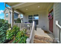 Charming covered front porch with decorative wreath and inviting seating area with small table and plants at 117 Stowe Rd, Belmont, NC 28012