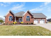 Charming brick home featuring a manicured lawn, attached two-car garage, and covered front porch at 9016 Heather Trce, Gastonia, NC 28056