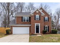 Charming two-story brick home with a well-manicured lawn, attached garage and a black front door at 10211 Ridgewell Ct, Charlotte, NC 28215