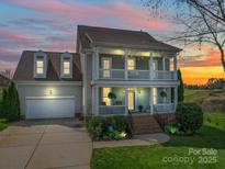 Charming two-story home with a welcoming porch and well-manicured landscaping at dusk at 139 Tenth Green Ct, Statesville, NC 28625