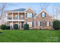 Inviting two-story brick home featuring a well-manicured lawn and double porches at 1812 Mill Chase Ln, Waxhaw, NC 28173