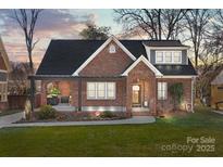 Charming brick home features a covered porch and manicured front lawn at 329 Fannie Cir, Charlotte, NC 28205