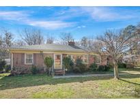 Charming brick home with a well-maintained lawn and mature landscaping under a beautiful blue sky at 3901 Starmount Ave, Charlotte, NC 28269