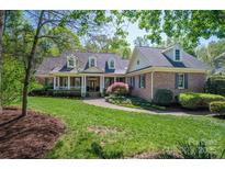 Charming brick home with a landscaped yard, inviting walkway, dormer windows and covered front porch with white columns at 13822 Tributary Ct, Davidson, NC 28036