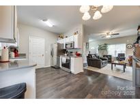 Modern kitchen featuring stainless steel appliances, dark wood floors, and an open layout to the living room at 140 Reid Ln, Pineville, NC 28134