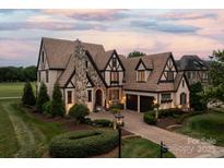 Charming Tudor-style home boasting stone accents, a brick driveway, and lush landscaping at 314 Royal Crescent Ln, Waxhaw, NC 28173