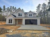 Charming two-story home with light beige siding, black roof, and an open two-car garage nestled in a wooded lot at 44401 Us 52 N Hwy, Richfield, NC 28137