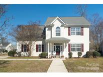 Charming two-story home with white siding, red shutters, and a well-manicured front yard at 7001 Conifer Cir, Indian Trail, NC 28079