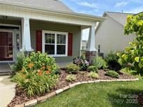 Charming home exterior featuring a lush landscaped front yard with vibrant flowers and well-maintained lawn at 822 Wisteria Way, Salisbury, NC 28146