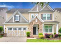 Charming two-story home featuring a stone archway, a two car garage, and manicured landscaping in the front yard at 1012 Equipoise Dr, Indian Trail, NC 28079