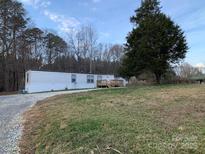 Charming single-story home with a gravel driveway, grassy yard, and mature trees at 150 Twisted Oak Ln, Gastonia, NC 28052