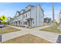 New townhome build featuring cement sidewalks, gray siding, black shutters, and roof dormers at 206 Freeland Ln, Charlotte, NC 28217