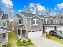 Beautiful two-story townhome with gray siding, stone accents, and a spacious two-car garage with green lawn at 3512 Auburn Curb Rd, Charlotte, NC 28217