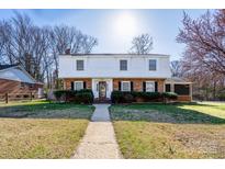 Charming two-story brick and white home with mature landscaping, featuring black shutters and a well-manicured front lawn at 6035 Idlebrook Dr, Charlotte, NC 28212