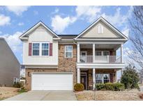Two-story brick home with two-car garage, front porch, second-floor balcony, and manicured lawn at 6211 Canyon Trl, Denver, NC 28037