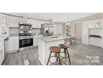 Modern kitchen features stainless steel appliances, granite countertops, and a center island with bar stool seating at 140 Sanford Ln, Badin Lake, NC 28127