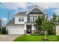 Charming two-story home featuring stone accents, a covered porch, and lush landscaping at 16725 Cozy Cove Rd, Charlotte, NC 28278