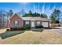 Charming brick home featuring green shutters, a well-manicured lawn, and attached garage at 2107 Summerfield Cir, Conover, NC 28613