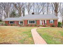 Charming single-story brick home featuring a walkway, manicured lawn, and mature trees at 329 N Oakwood Dr, Statesville, NC 28677