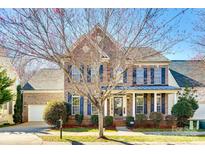 Beautiful two-story brick home with mature landscaping, attached garage, and charming front porch with blue shutters at 8315 Bridgegate Dr, Huntersville, NC 28078