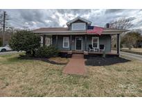 Charming home featuring a quaint porch, American flag, and well-manicured landscaping, exuding curb appeal at 101 Sunset Dr, Stanley, NC 28164