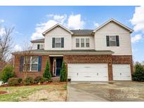 Inviting two-story home featuring a brick facade, dormers, two-car garage and well-manicured front yard at 11296 Serenity Farm Dr, Midland, NC 28107