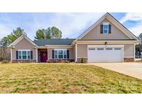 Charming single-story home featuring a two-car garage, well-manicured lawn, and inviting entrance with a decorative wreath at 136 Falls Leaf Dr, Troutman, NC 28166